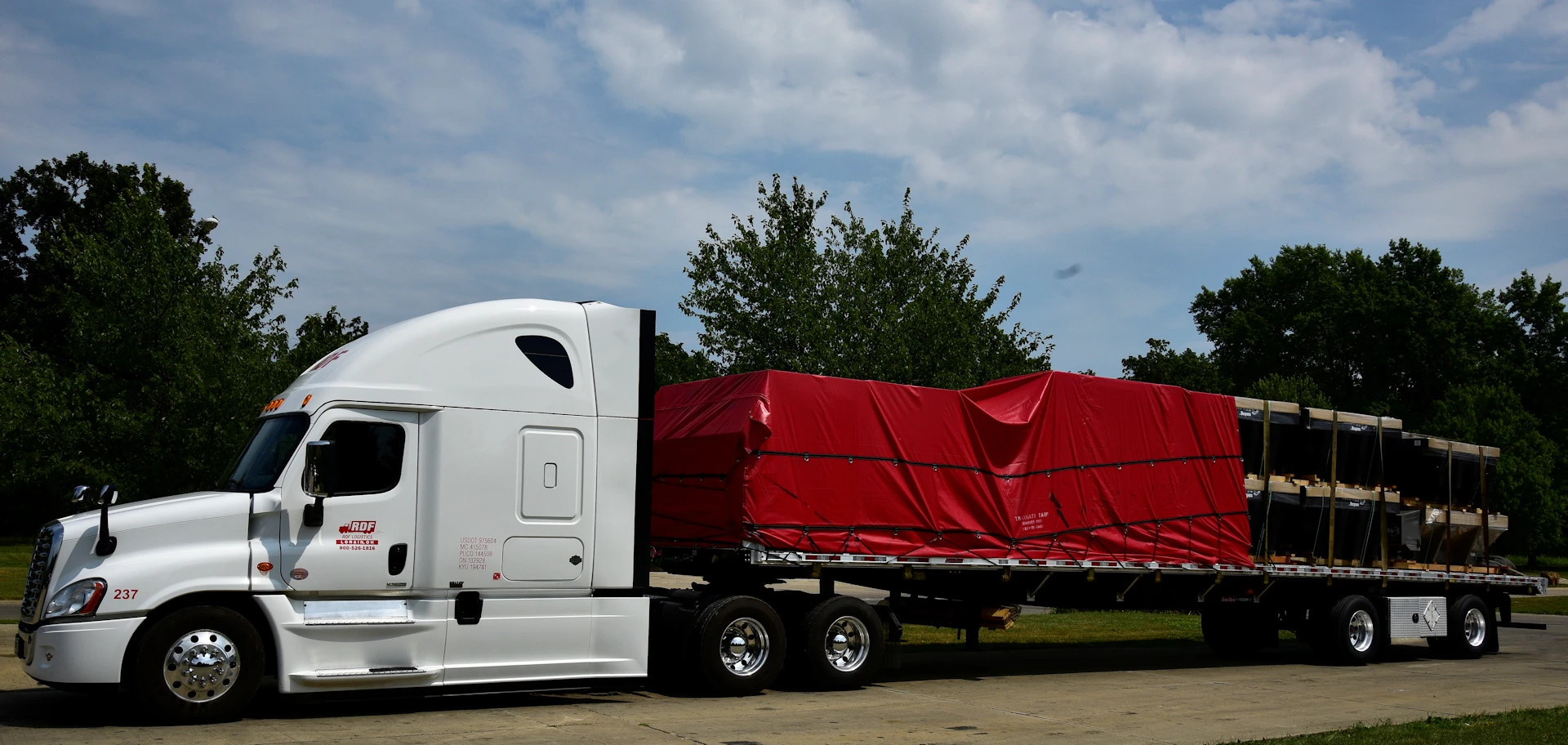 RDF flatbed truck carrying a secured, tarped load
